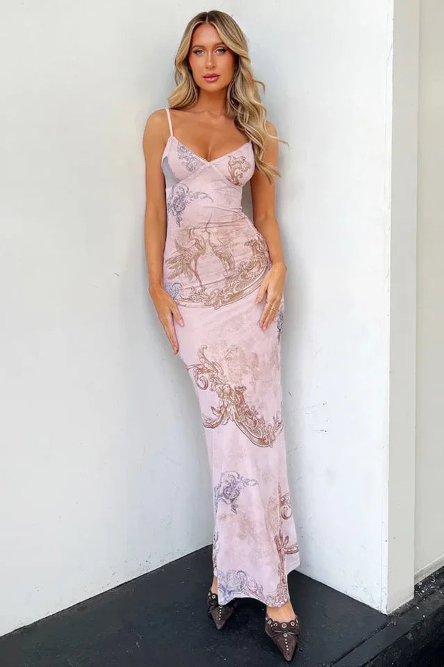 Woman wearing a pink sheer mesh maxi dress with a baroque print, featuring spaghetti straps and a scoop neckline.