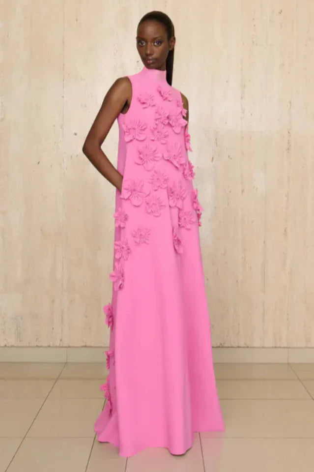 Woman wearing a long pink sleeveless dress with appliqué floral details and pockets. Main image
