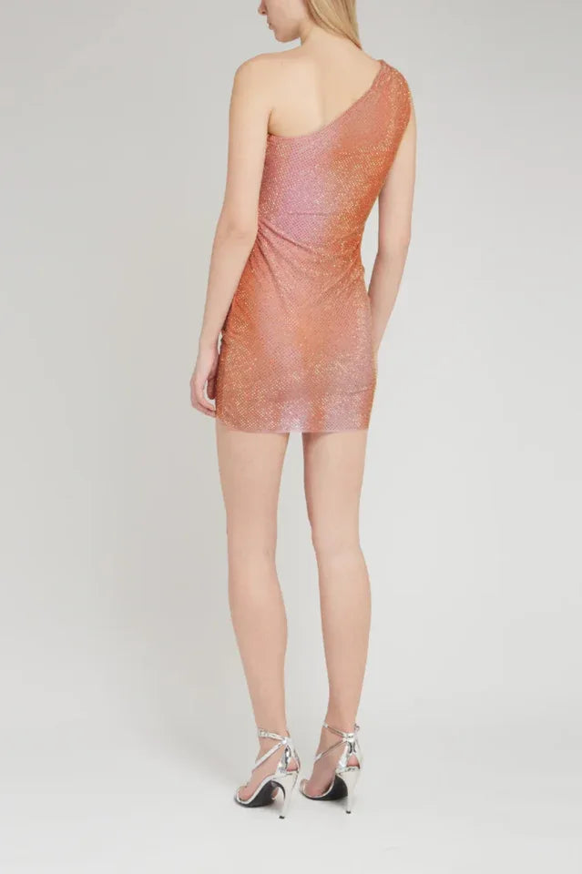 Back view of a woman in a shimmering one-shoulder mini dress with ruching and asymmetrical hem.