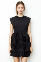 Woman wearing a black mini dress with floral embellishments on the skirt and a high neckline.
