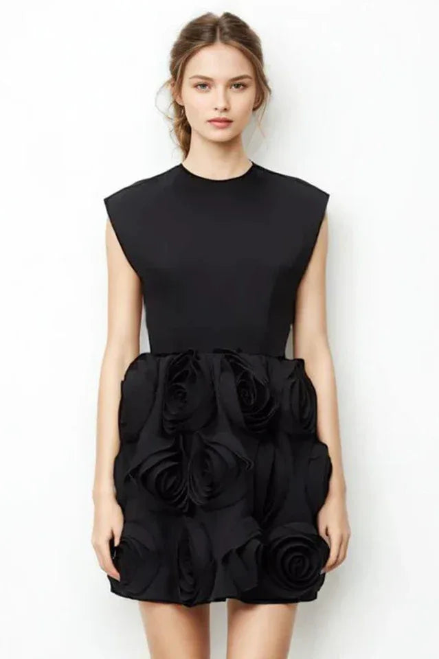 Woman wearing a black mini dress with floral embellishments on the skirt and a high neckline.