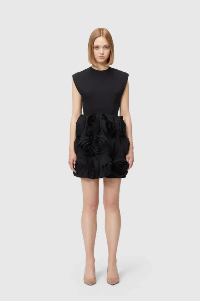 Full body shot of a woman in a black mini dress with floral embellishments.