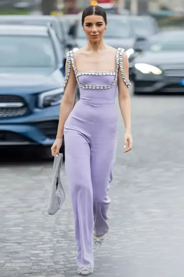 Woman walking outdoors in a lavender jumpsuit with embellished straps and wide legs