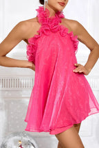 Close-up of a woman in a hot pink ruffled halter dress, showcasing the sheer fabric.