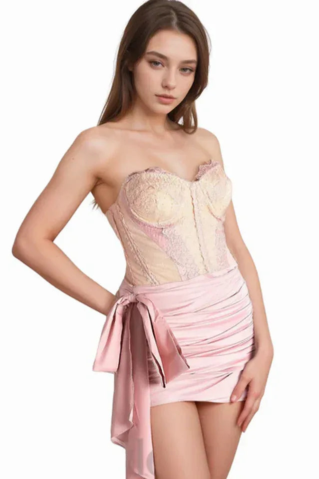 Model wearing a pink strapless mini dress with lace bodice and bow detail