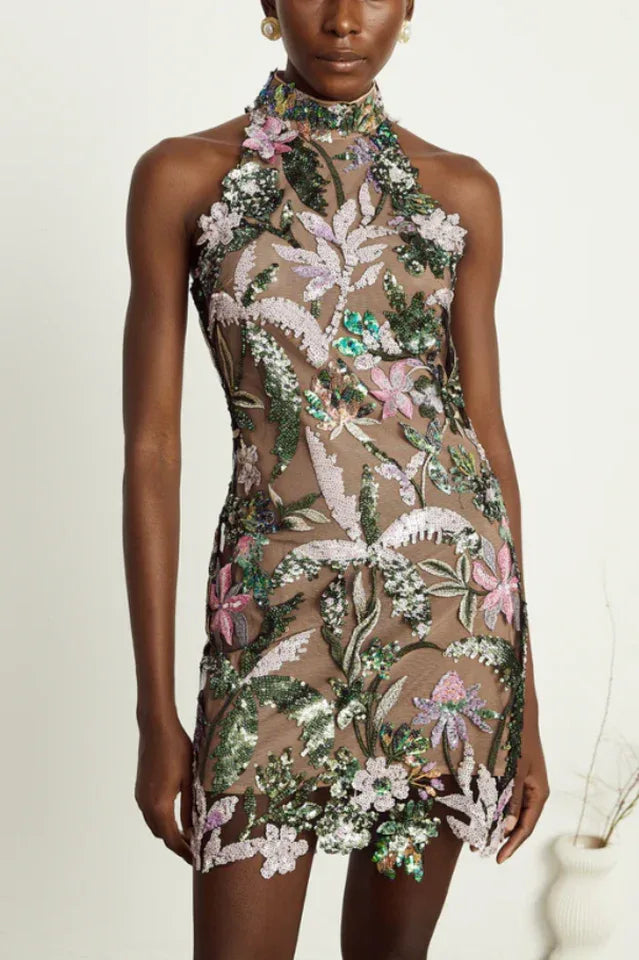 Woman wearing a sleeveless, sheer mini dress with colorful floral embroidery and sequins, featuring a halter neckline. Main image