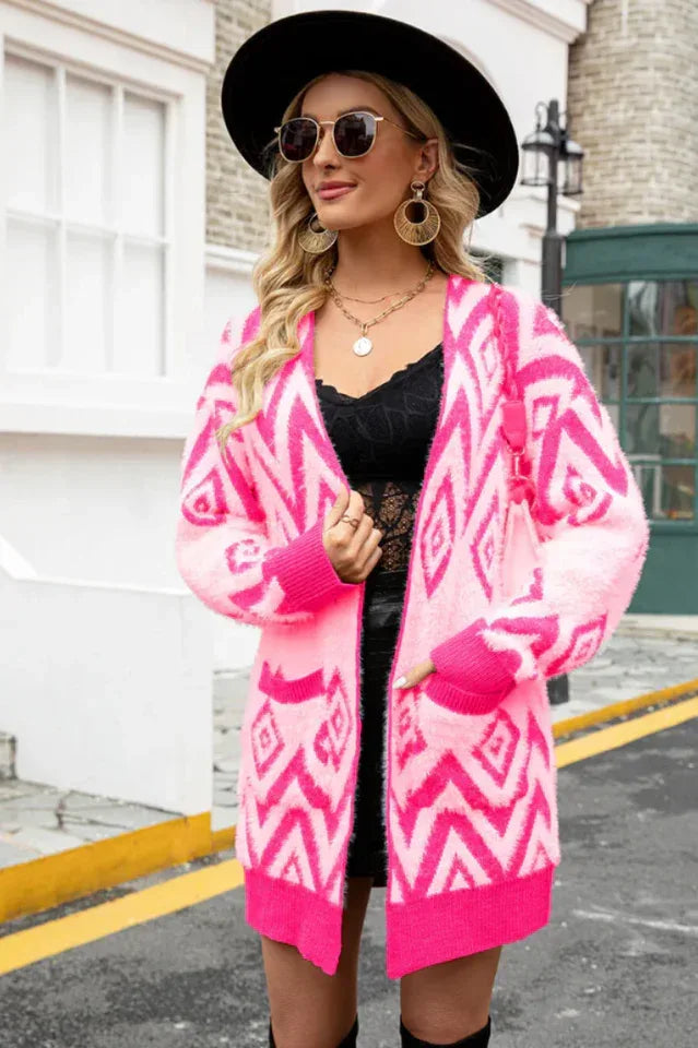 Woman wearing a pink and white geometric pattern fuzzy knit cardigan with pockets and an open front. Main image