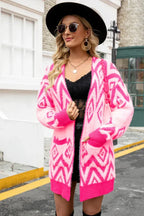 Woman wearing a pink and white geometric pattern fuzzy knit cardigan with pockets and an open front.