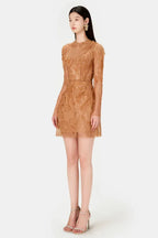 Side profile of a woman wearing a tan lace mini dress with long sleeves.