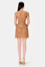Back view of a woman in a tan lace mini dress with long sleeves.