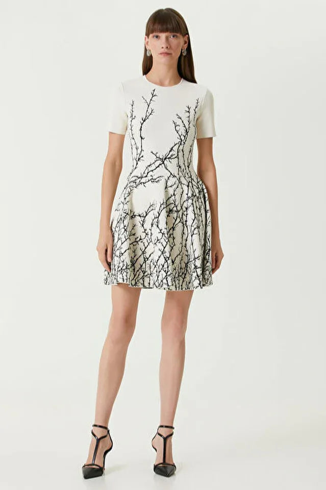 Woman wearing a white short-sleeve dress with a black branch print