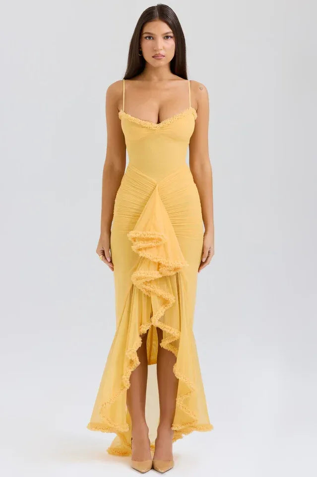 Woman wearing a yellow ruched mesh evening dress with spaghetti straps and a ruffled asymmetrical hemline. Main image