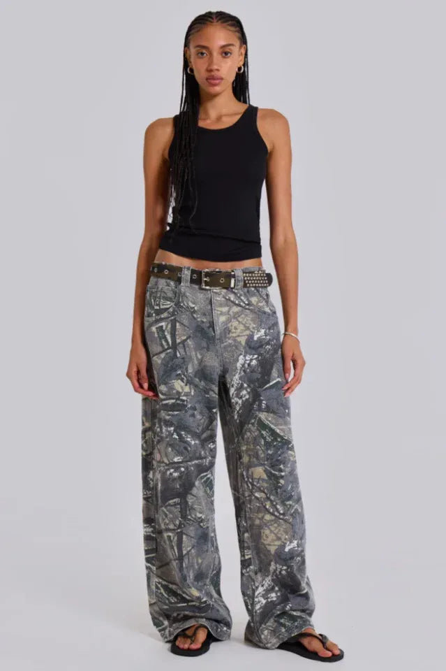 Model wearing wide leg camouflage print denim pants and a black tank top, front view. Main image