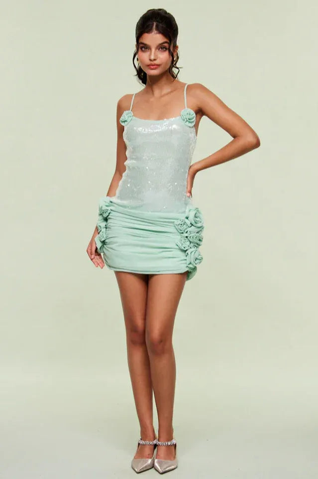 Full body shot of a woman in a mint sequin mini dress with floral details
