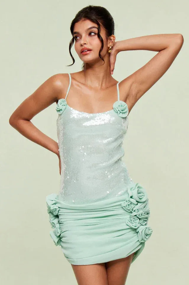 Woman wearing a light mint sequin mini dress with floral applique and ruched skirt