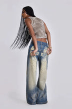 Close-up of woman's torso and legs showing the pleated detail on light wash denim jeans