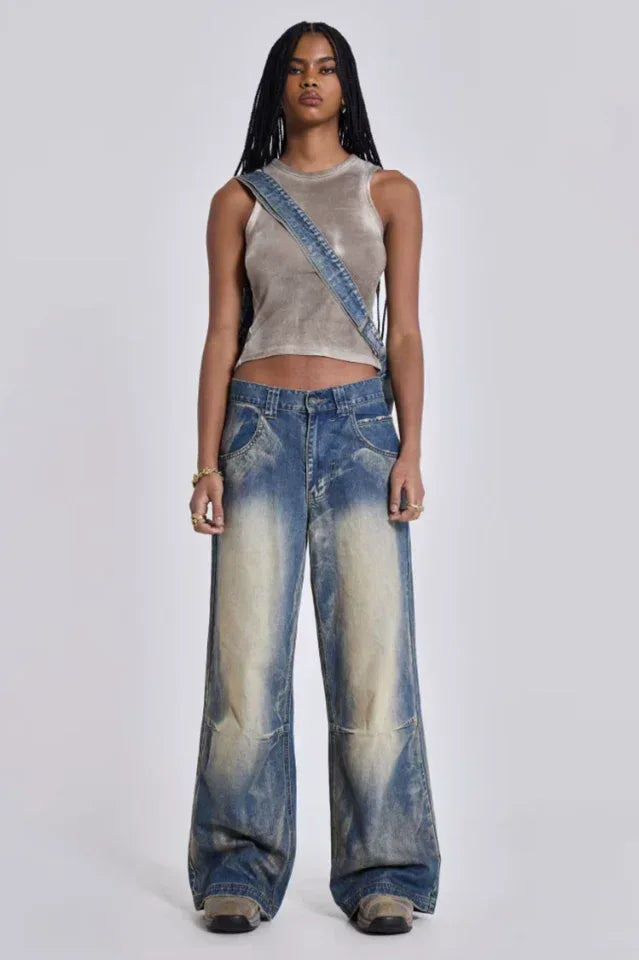 Woman wearing wide leg light wash denim jeans with pleated front pocket detail and a cropped tank top Main image