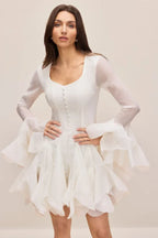 Model wearing a white fit and flare dress with flared sheer sleeves and a ruffled skirt.