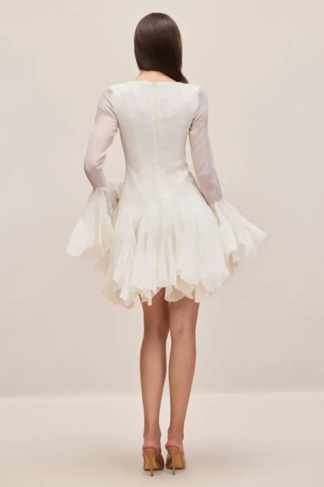 Back view of a white dress with long sheer sleeves and a flounced hem.