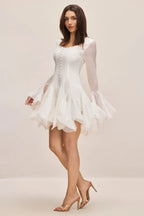 Side view of a model in a white party dress with layered ruffles.