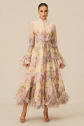 Front view of a woman showcasing a formal chiffon dress with a detailed floral and butterfly print, featuring a button placket and flared sleeves.