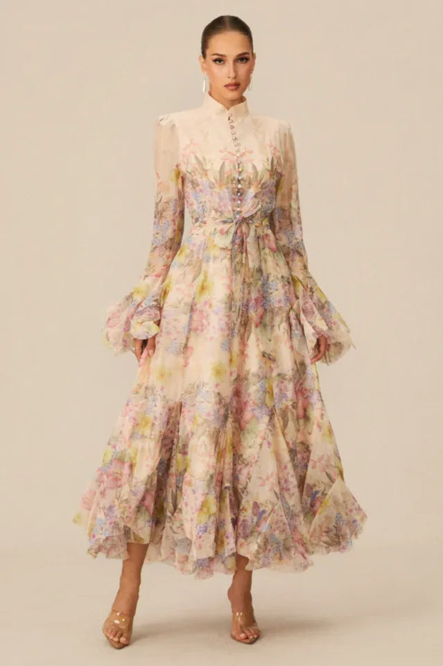 Front view of a woman showcasing a formal chiffon dress with a detailed floral and butterfly print, featuring a button placket and flared sleeves.