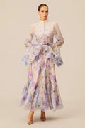 Full-length view of a woman in a pastel floral print maxi dress with dramatic bell sleeves and a self-tie waist.