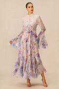 Side profile of a woman modeling a light, airy floral dress featuring ruffled tiers and statement sleeves.