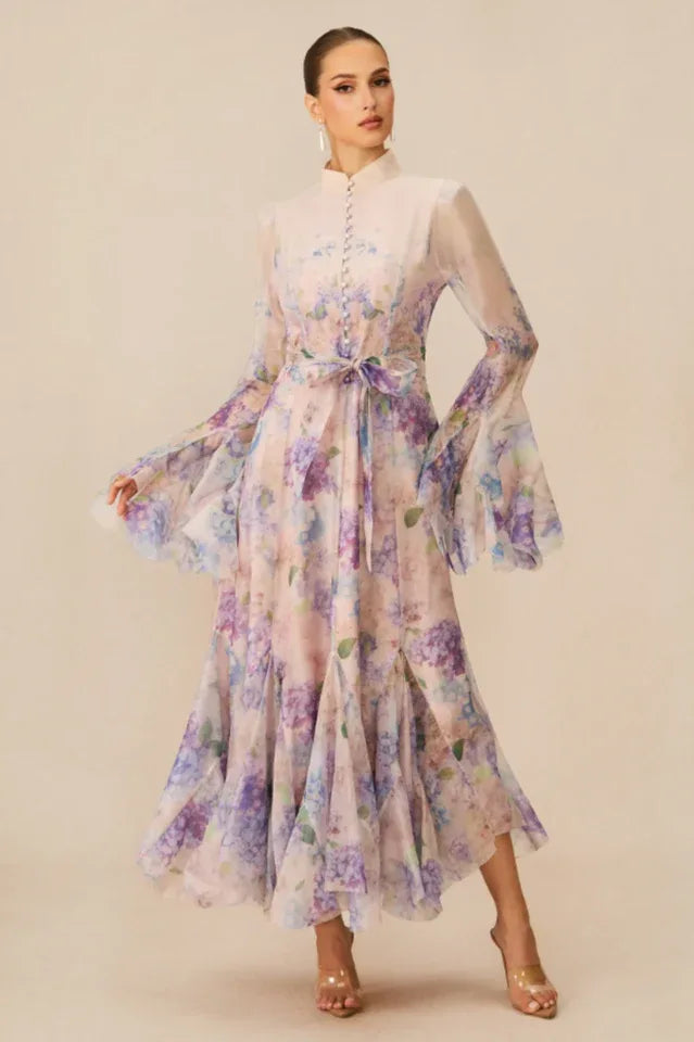 Side profile of a woman modeling a light, airy floral dress featuring ruffled tiers and statement sleeves.