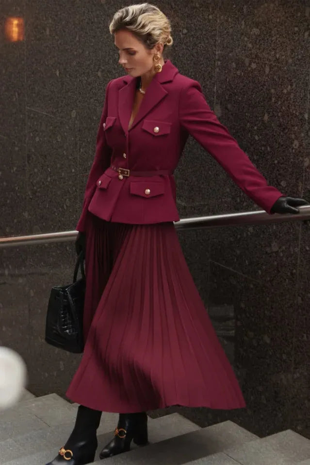 Woman wearing a burgundy suit with a pleated skirt and blazer Main image