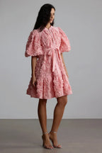 Woman posing in a pink textured floral mini dress