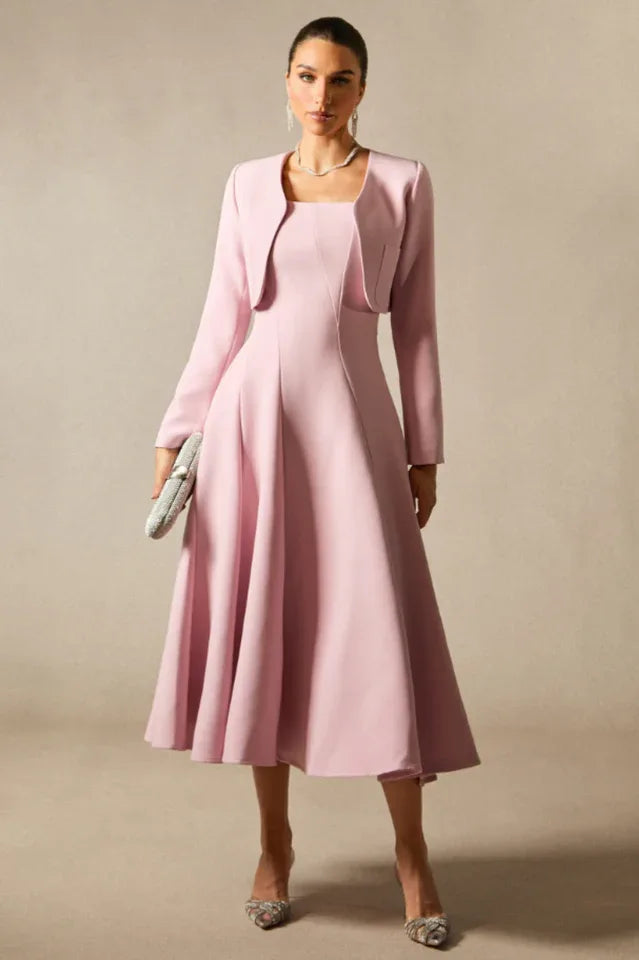 Woman wearing a pink formal dress with a matching jacket, holding a silver clutch.
