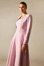 Side profile of a woman in a pink formal dress and jacket, emphasizing the fabric texture and silhouette.