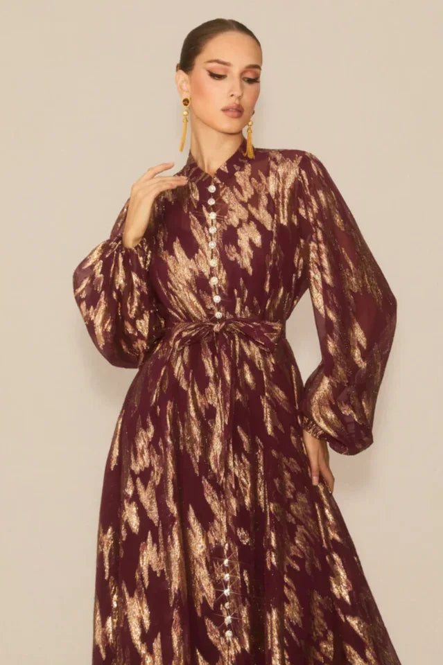 Close-up of the bodice of a burgundy and gold abstract print maxi dress, showing pearl buttons and high neckline
