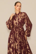 Close-up of the bodice of a burgundy and gold abstract print maxi dress, showing pearl buttons and high neckline