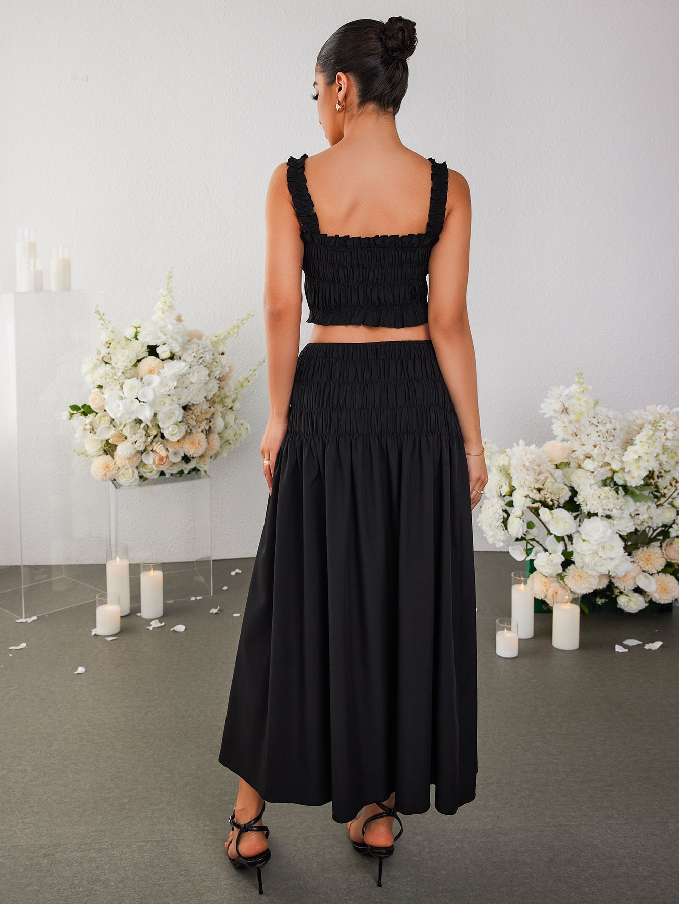 Back view of a woman in a black smocked crop top and maxi skirt