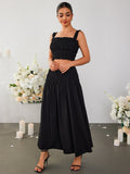 Woman in a black smocked crop top and maxi skirt showing off jewelry