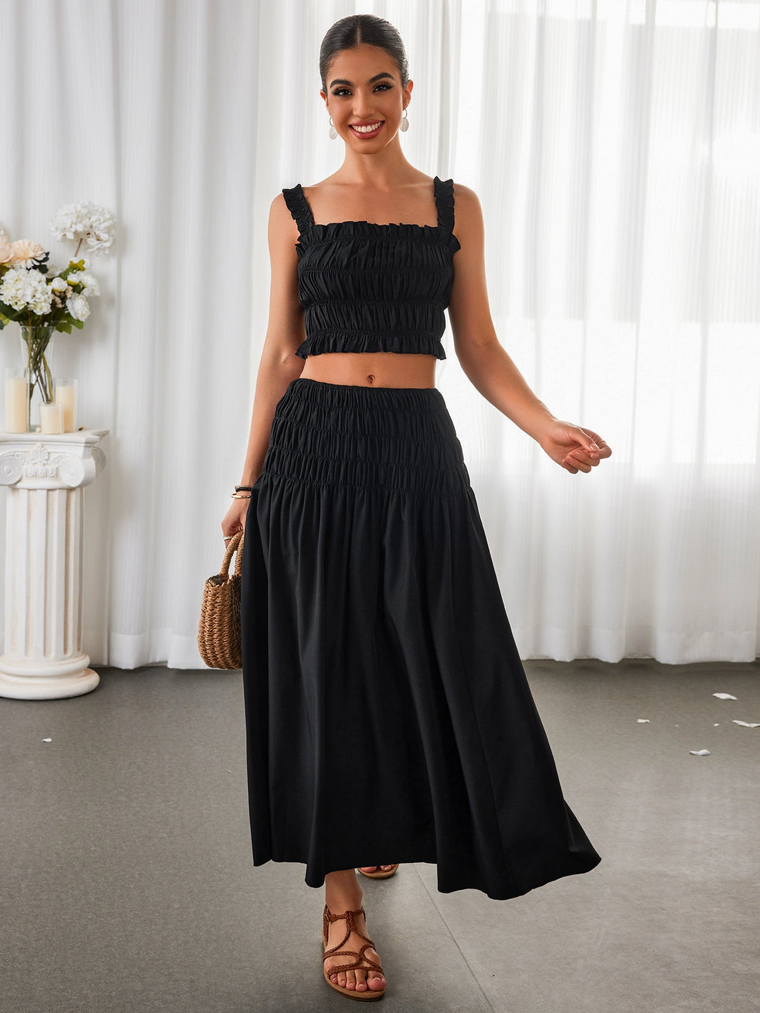Woman wearing a black smocked crop top and a black smocked maxi skirt