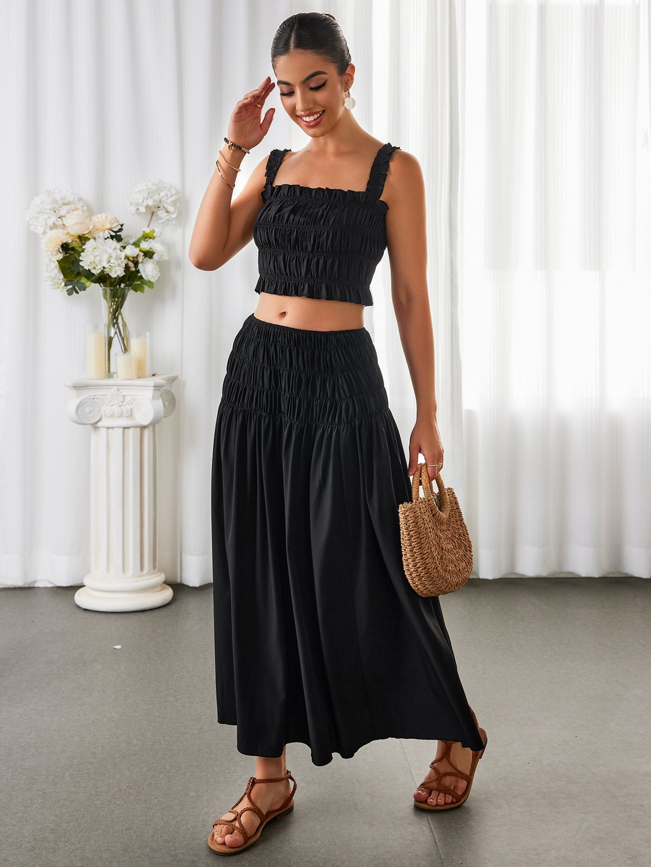 Woman in a black smocked crop top and maxi skirt with hand on forehead