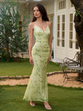 Full body shot of a woman in a light green floral print maxi dress with spaghetti straps, standing in a garden