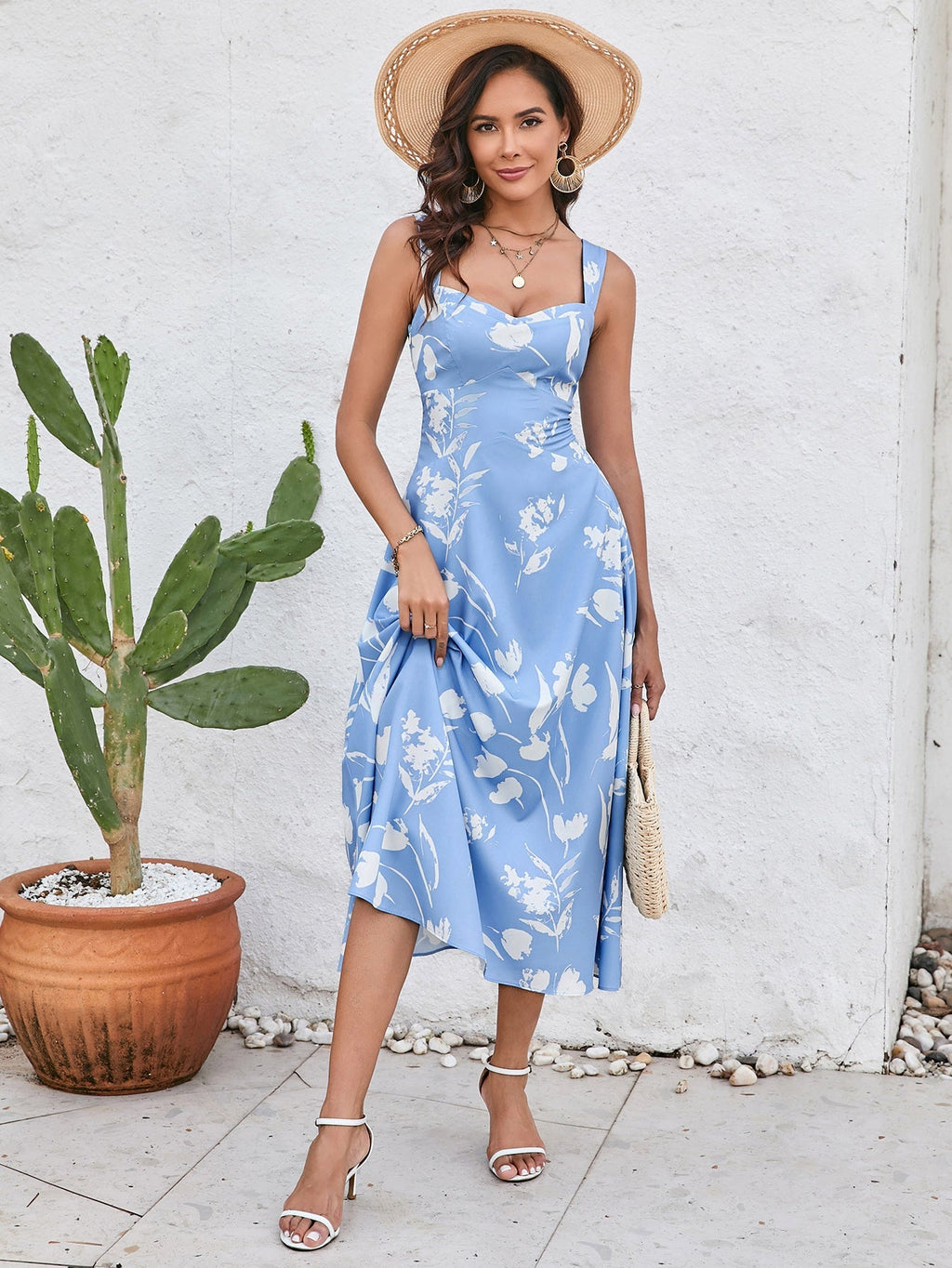 Woman lifting the hem of a blue floral print midi dress, showcasing the midi length.