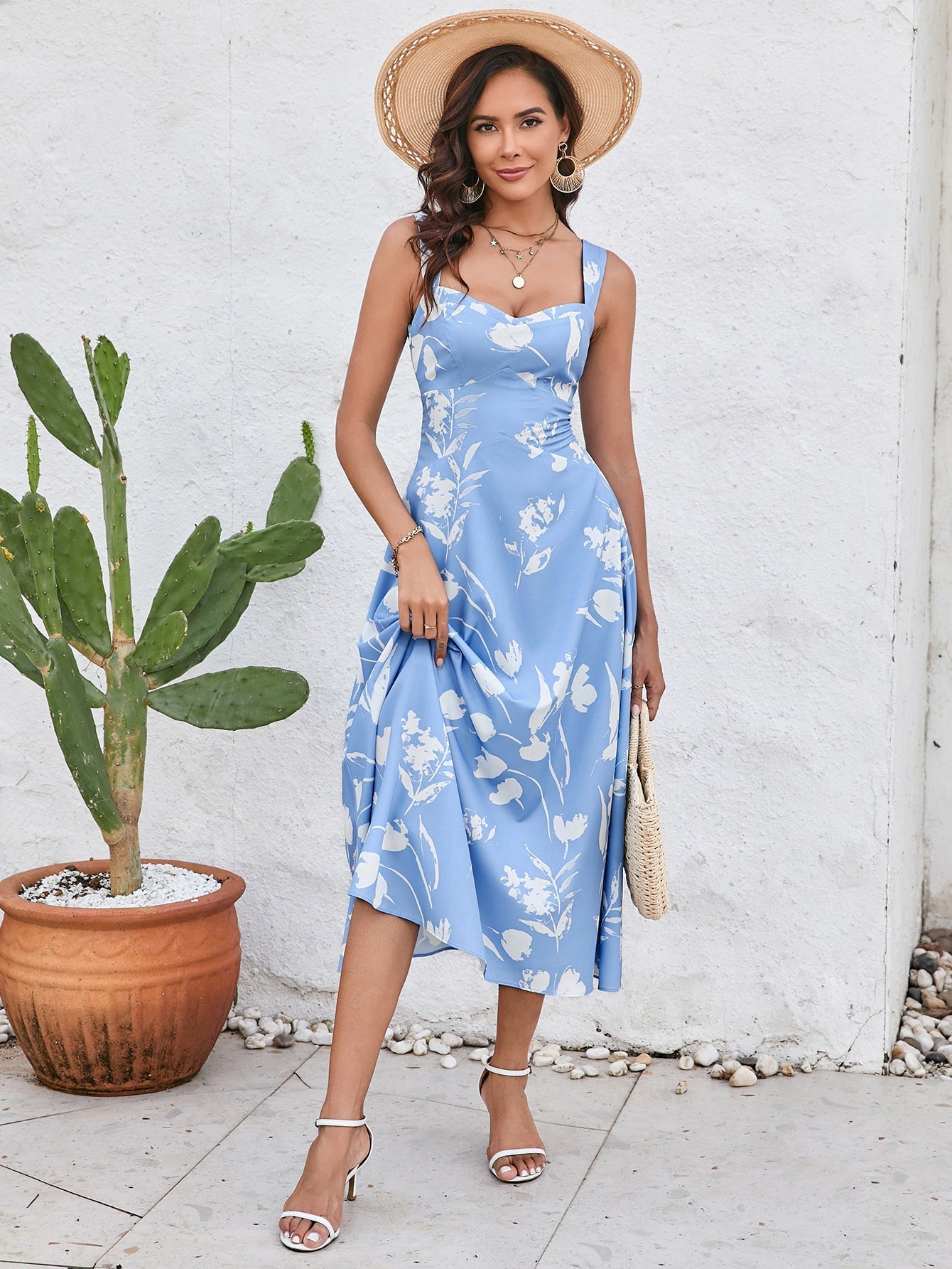 Woman lifting the hem of a blue floral print midi dress, showcasing the midi length.