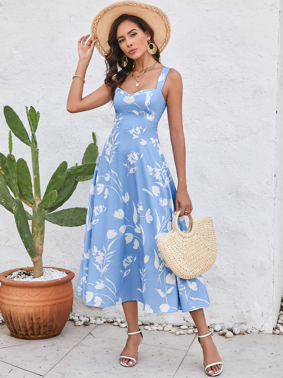 Woman wearing a blue floral print midi dress with a square neckline and spaghetti straps.