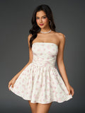 Woman wearing a strapless floral print mini dress with a ruched bodice and a large bow detail at the back.