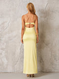 Back view of a woman in a pale yellow satin formal gown, showcasing an open back with a clasp detail and floor-length hem.