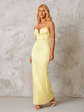 Side profile of a woman wearing a pale yellow satin formal gown with thin spaghetti straps and a floor-length mermaid silhouette.