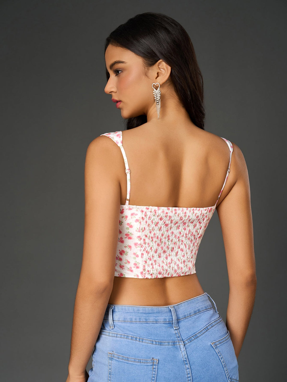 Woman wearing a white floral print cropped top with a sweetheart neckline and wide tank straps.