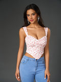 Front view of a woman in a white floral print cropped top with sweetheart neckline and wide tank straps, paired with blue jeans.