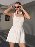 Woman adjusting sunglasses while wearing a white sleeveless mini dress