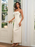 Woman in a long, ivory strapless satin gown with a sweetheart neckline, posing by a door.